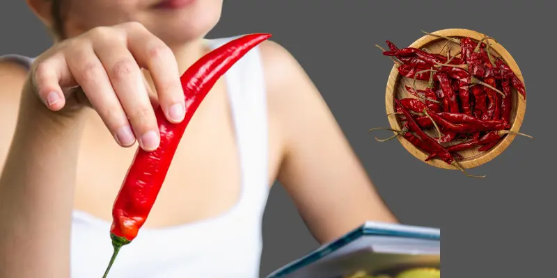 A Girl Is Holding A Chilli With A Plate Full Of Chillies Girl is holding a chilli with a plate full of chillies.