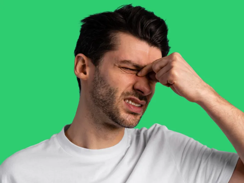 Man is clinching his nose base near the eyes because of eye pain